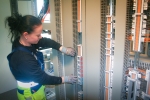 Inde en af de to relæbygninger på Apples kommende energiforsyningsstation går automationstekniker Kasia Dahl Svendsen rundt mellem de mange tavler. 800-900 kabler skal tilsluttes i hver bygning, og derfra bliver selve omkoblingen styret. Med sine 155 cm er det ofte hende, der bliver sendt ned under gulvet for at montere kabler.
- Det er helt ok, der er plads nok dernede, griner hun.